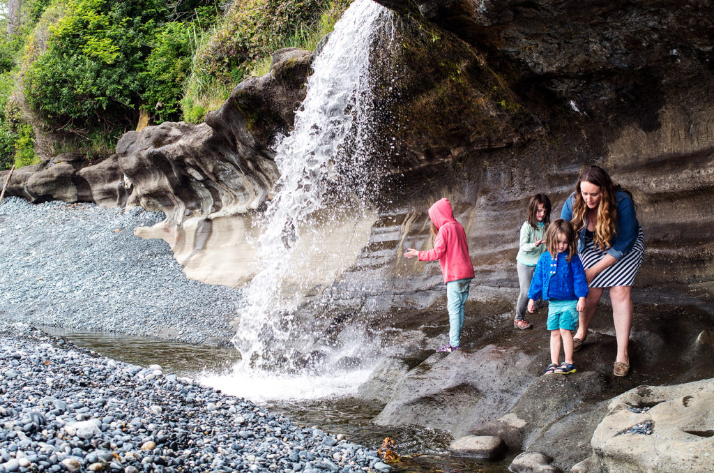 family under a waterfall at sandcut beach