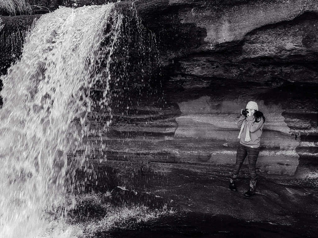 Ashley McMath taking a photo under a waterfall at Sandcut Beach Sooke BC
