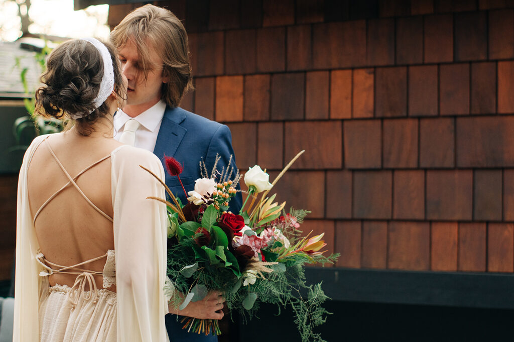 a bride and groom about to kiss. the photo shows he back of the bride's dress