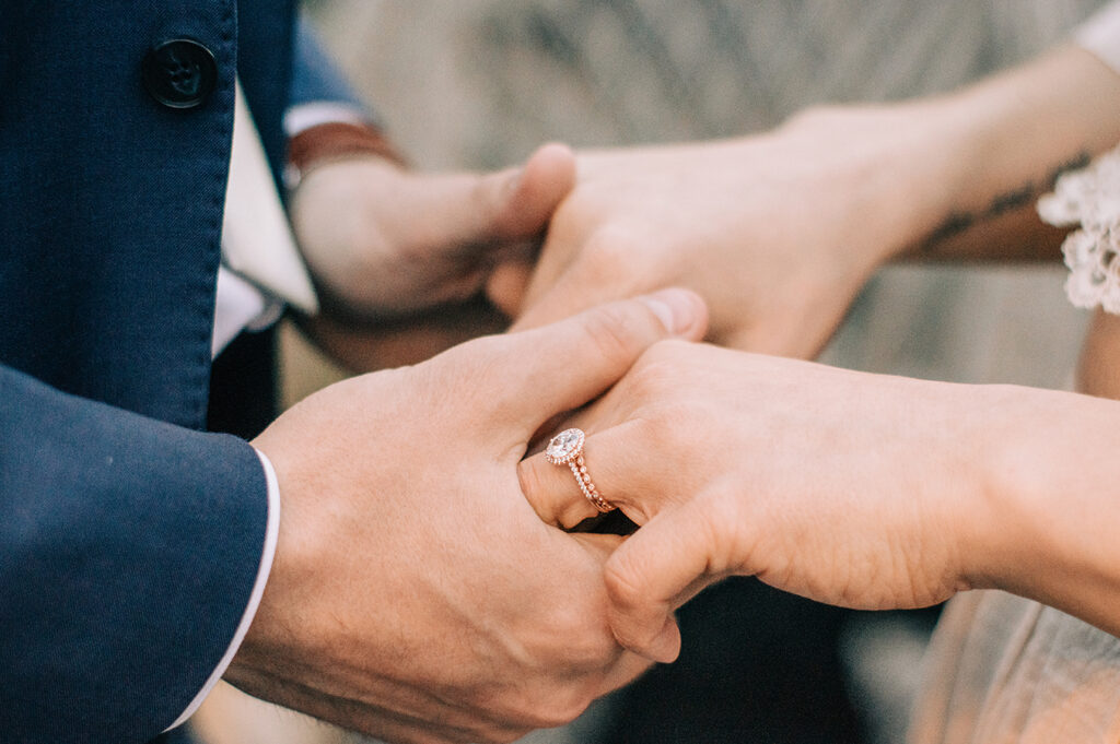 a bride and groom holding hands on their wedding day, with a wedding ring